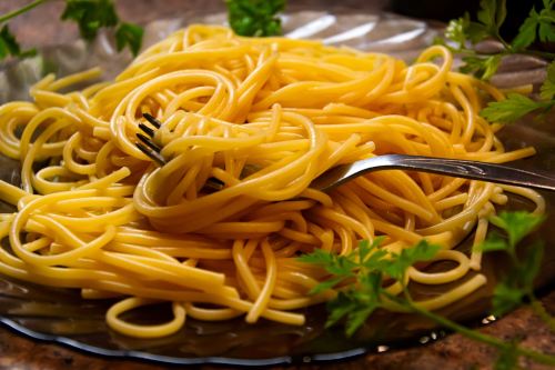 it's way more delicious than lego code though A plate of cooked spaghetti noodles with fork and a parsley garnish.