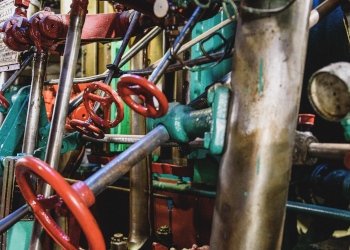 A cramped, confusing set of pipes and valves. Small red wheels for turning valves are attached to long steel-grey pipes. The overall impression is of a cluttered, complex engine.